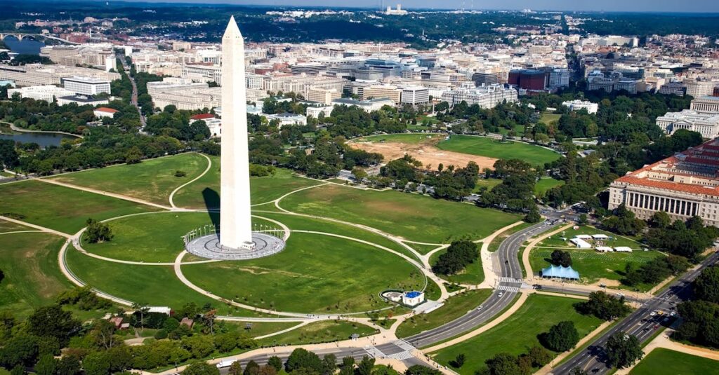 A breathtaking aerial view of the Washington Monument surrounded by cityscape and green landscapes.