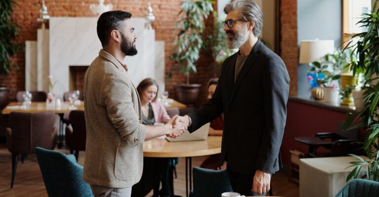 Two businessmen shaking hands in a stylish cafe, sealing a deal or agreement.