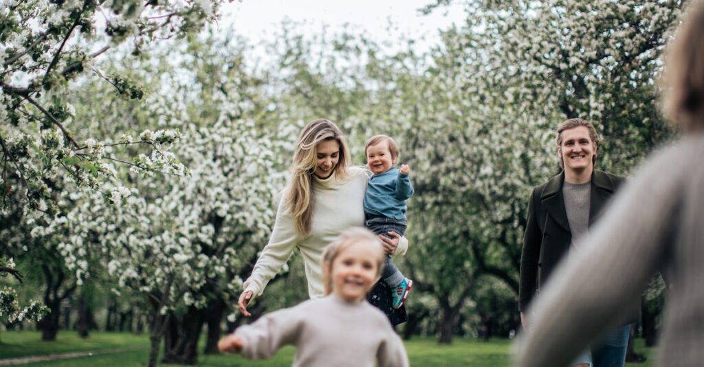 A joyful family enjoys a playful day outdoors amidst blossoming trees in spring.