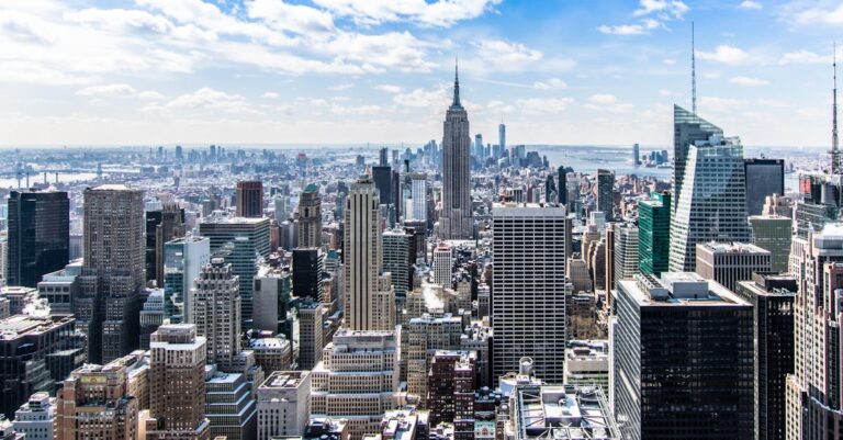 A stunning aerial view of New York City's skyline featuring the iconic Empire State Building under a bright blue sky.