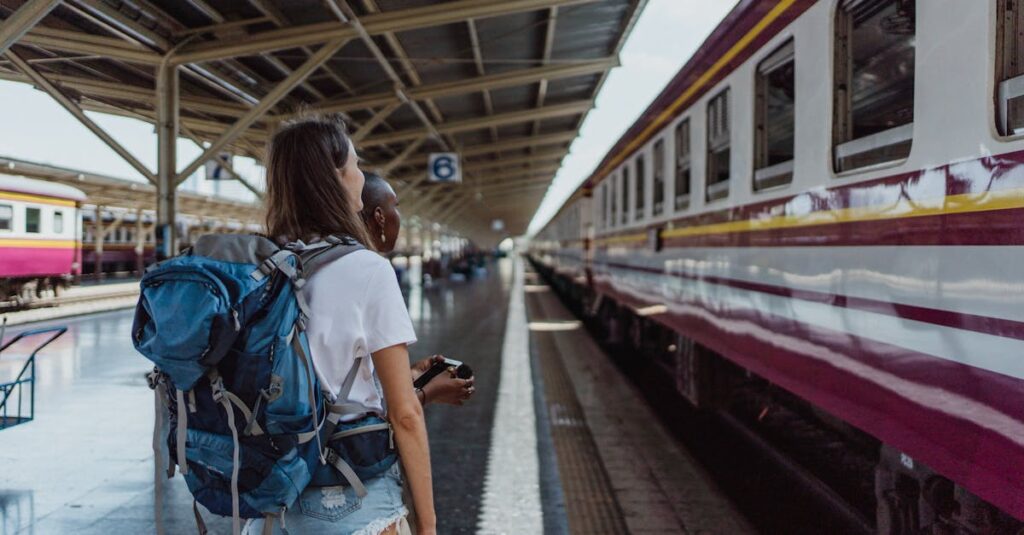 Two women with backpacks waiting at a railway station for a train. Travel and adventure theme.