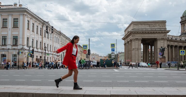 A woman in a fashionable red suit walks near the Kazan Cathedral in Saint Petersburg, Russia.