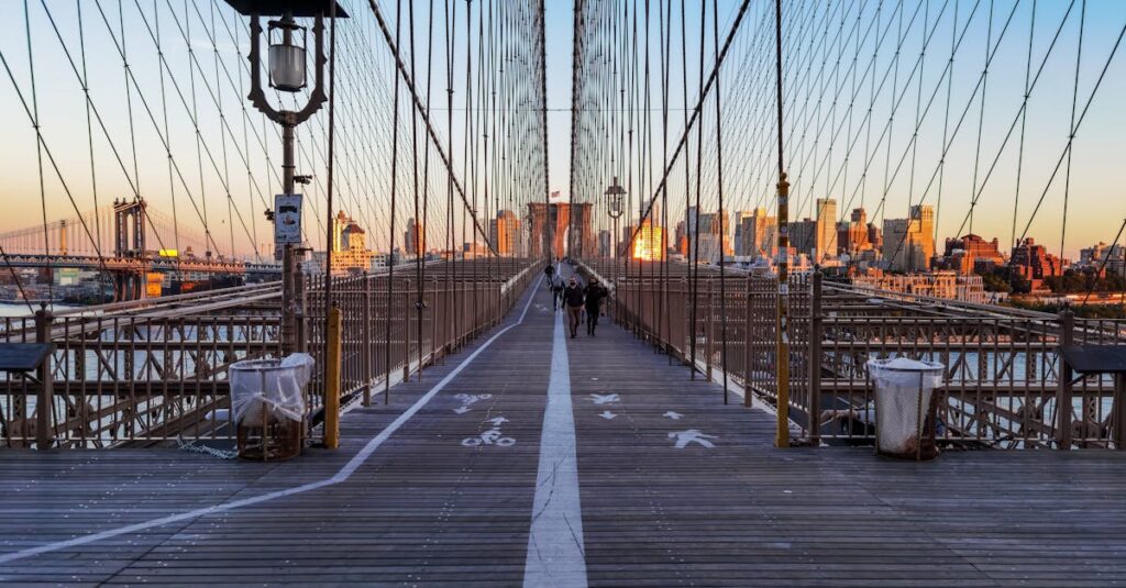 Scenic view of Brooklyn Bridge walkway with NYC skyline during twilight, showcasing iconic architecture.