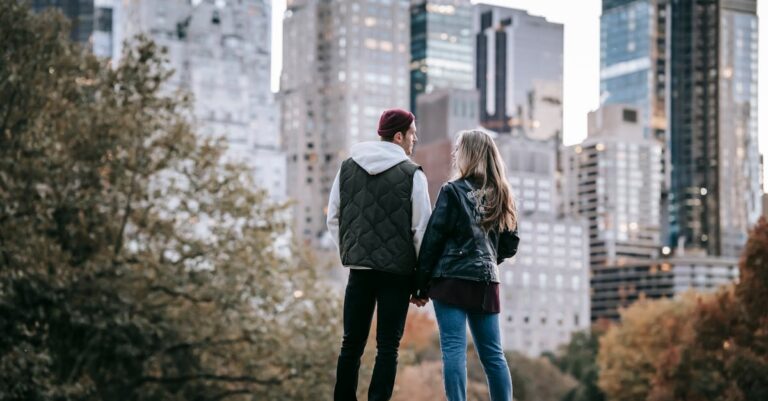 Young couple enjoying a romantic walk in the city during autumn with skyscrapers in the background.