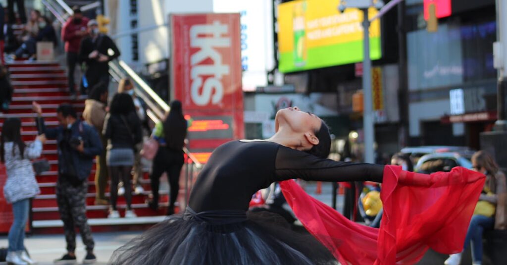 A graceful ballet dancer performs with a red scarf in Times Square, capturing movement and energy.