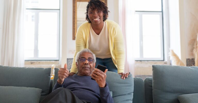 Smiling senior man and caregiver share a joyful moment at home.