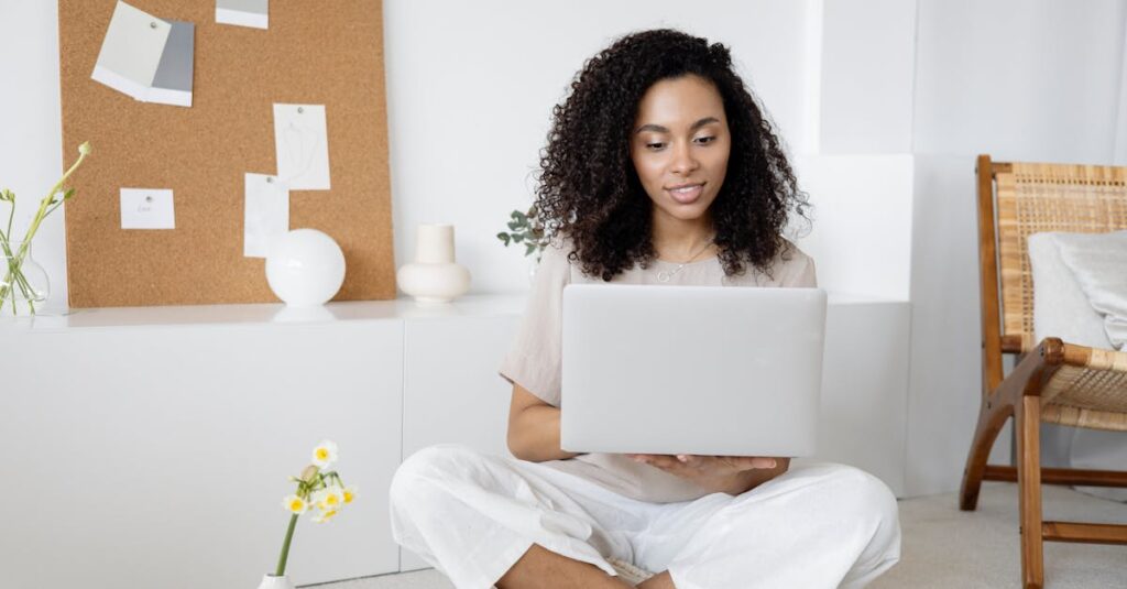 Young woman with curly hair working on her laptop in a cozy home setting, exuding confidence and focus.