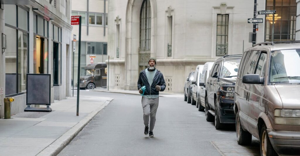 A man jogging on an urban street, surrounded by parked cars and tall buildings.