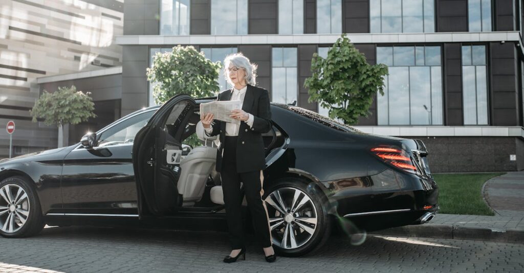 Professional adult woman in business attire reading beside a luxury car.