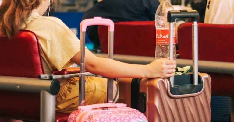 Passengers waiting with colorful luggage at an airport terminal, capturing travel and anticipation.