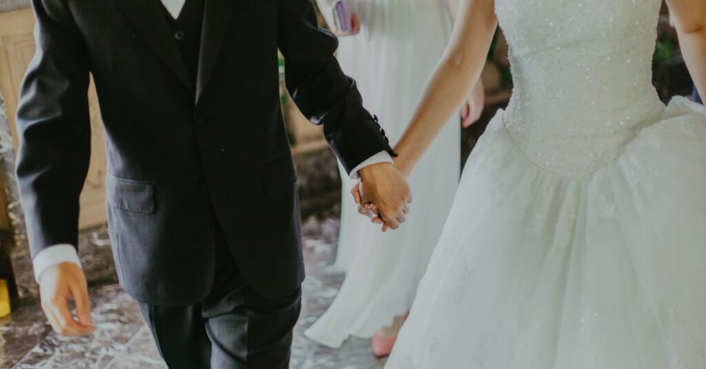 A romantic moment capturing a bride and groom holding hands in elegant wedding attire indoors.