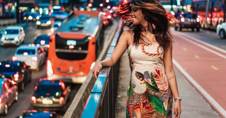 A joyful woman standing by city traffic, embodying vibrant urban life at night.