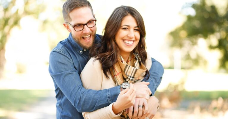 A happy couple enjoying an outdoor engagement photoshoot with laughter and love.