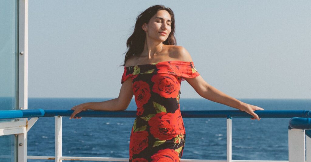 Woman in floral dress enjoying ocean view on a cruise ship under clear blue skies.