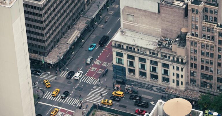 Busy New York City intersection with yellow cabs and skyscrapers, captured from above.