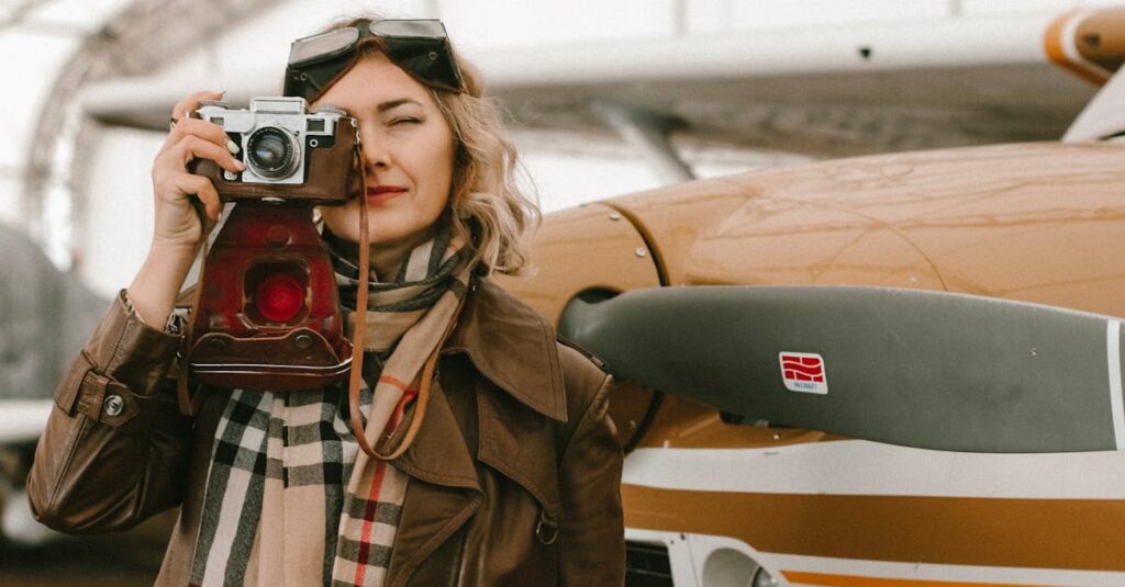 Fashionable woman with vintage camera posing by an airplane in an open hangar.