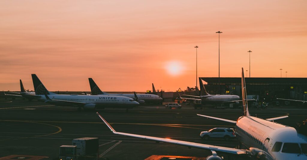 A serene view of parked airplanes at an airport with a beautiful sunset in the background.