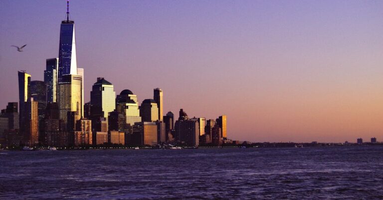 Breathtaking view of New York City skyline at sunset with waterfront and iconic skyscrapers.