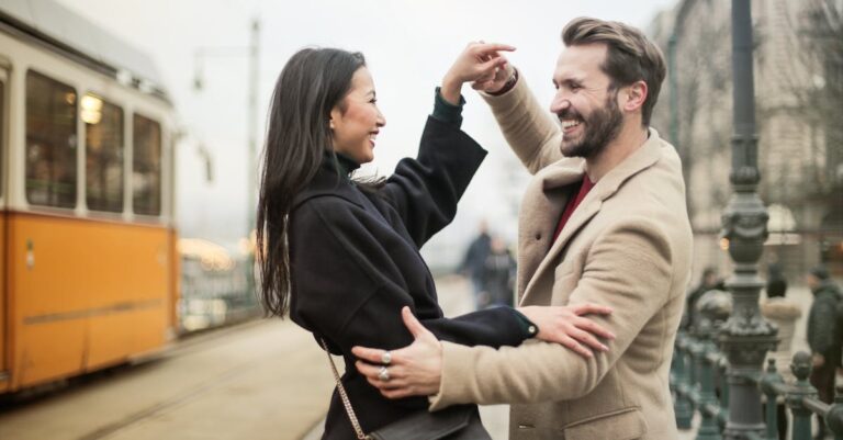 Joyful couple dances on a tram-lined city street, sharing laughter and happiness.