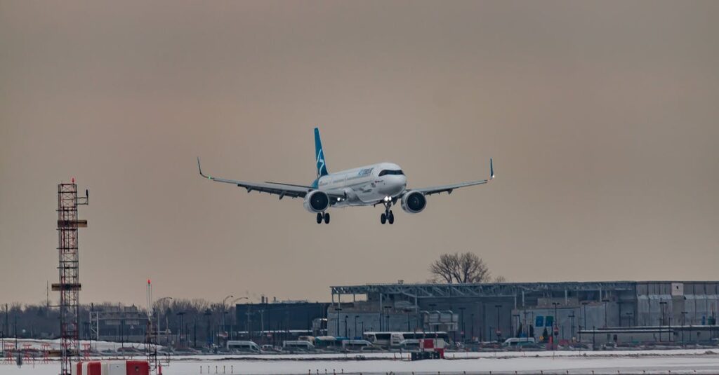 Powerful airplane flying over snowy terrain and preparing for landing on aerodrome airfield against cloudy sunset sky