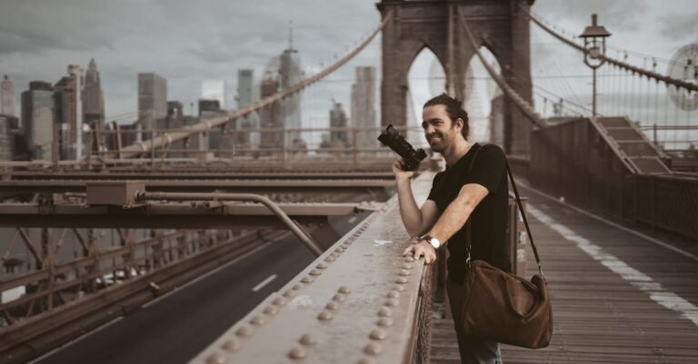 Man photographing on Brooklyn Bridge with New York City skyline in background.