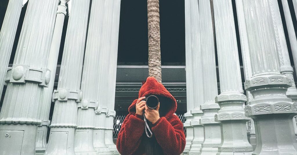 A photographer capturing the iconic Urban Light sculpture at LACMA in Los Angeles, illuminated at night.