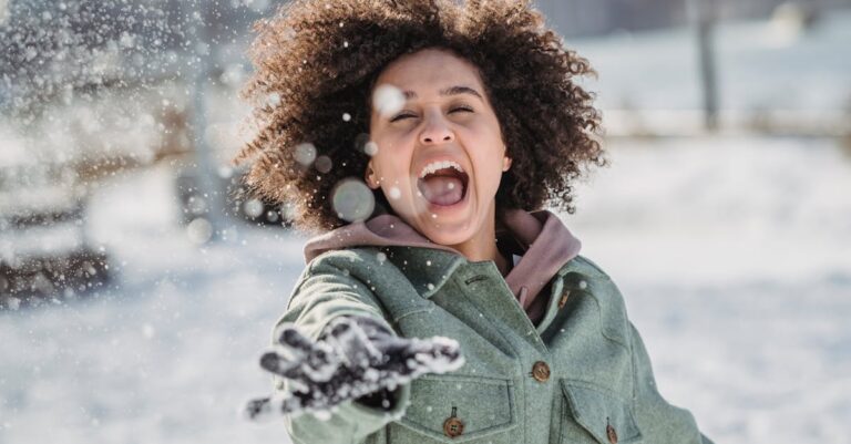 Cheerful woman enjoying a snowy day, playfully throwing snow in a winter park.