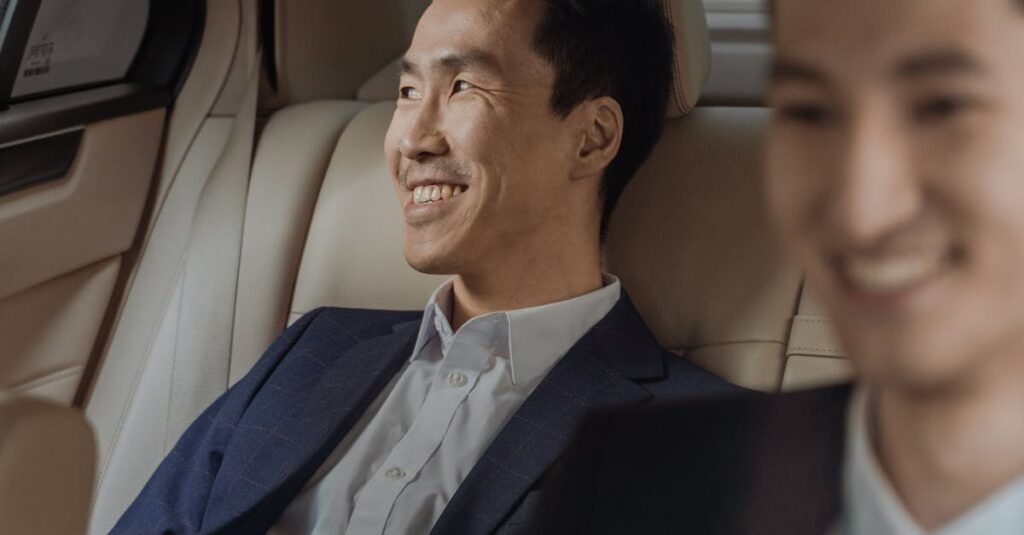 Two men in formalwear enjoying a comfortable ride in a luxury car, smiling.