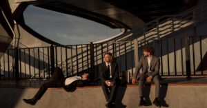 Three businessmen in suits sitting and relaxing outdoors under a modern bridge.