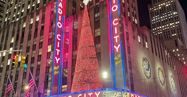 Night scene of Radio City Music Hall in New York City, beautifully lit up with festive lights.