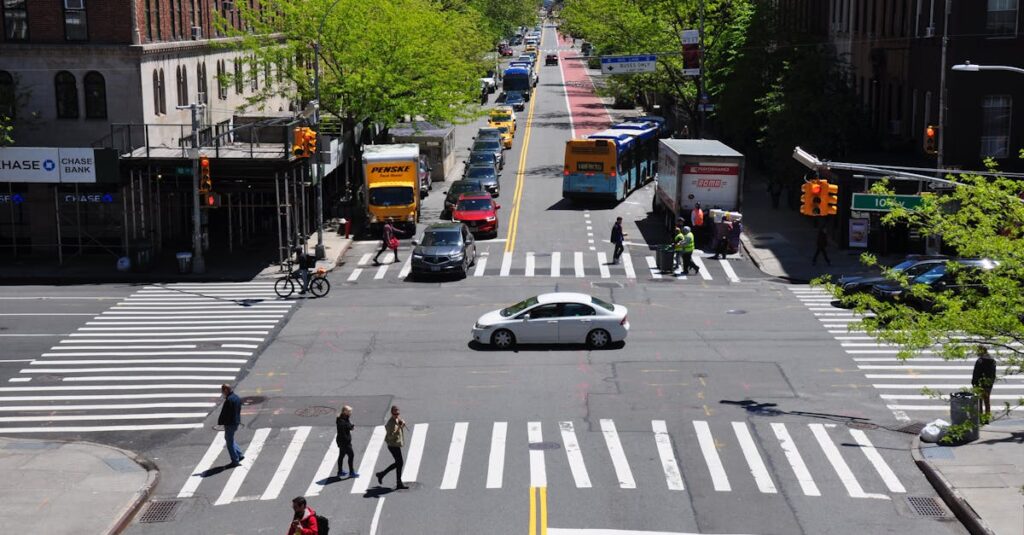 A bustling New York City intersection with cars, buses, and pedestrians on a sunny day.