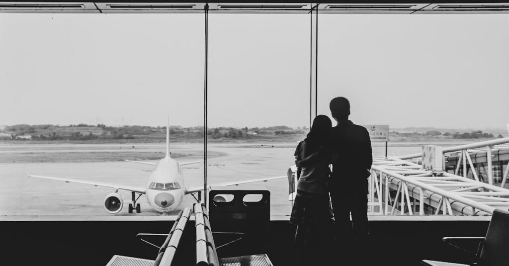 Silhouette of a couple embracing while watching an airplane at a modern airport terminal.