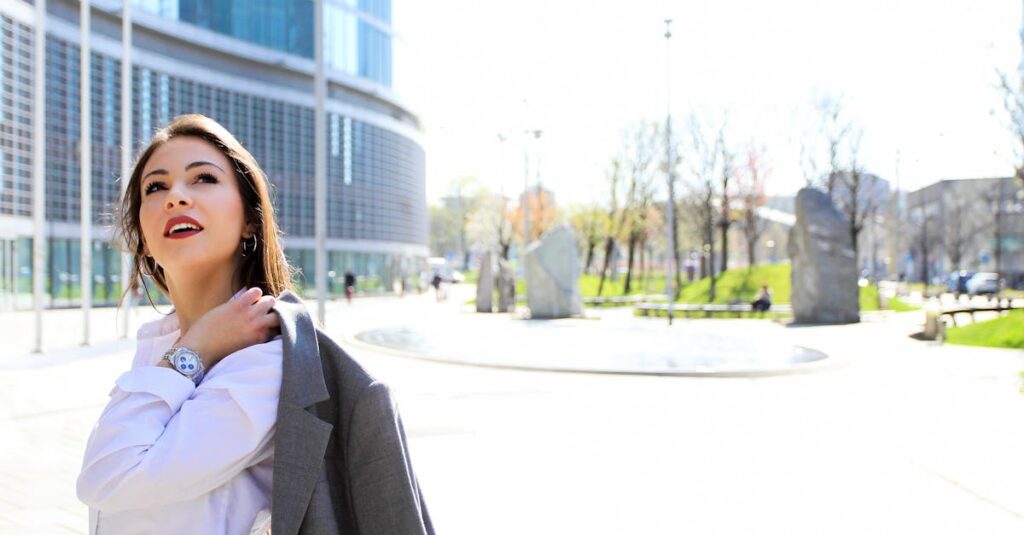 Smiling businesswoman outdoors with modern architecture background. Bright sunny day.