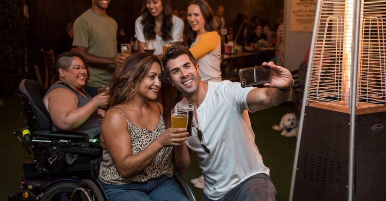 A cheerful group of friends taking a selfie with drinks at an indoor party.