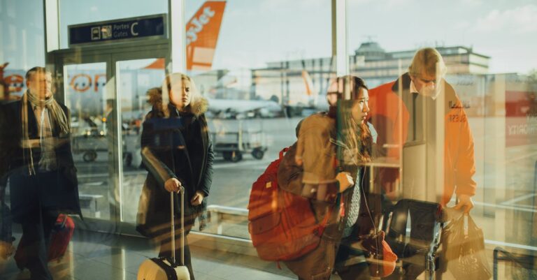 Passengers moving through an airport gate area with visible airplanes outside.