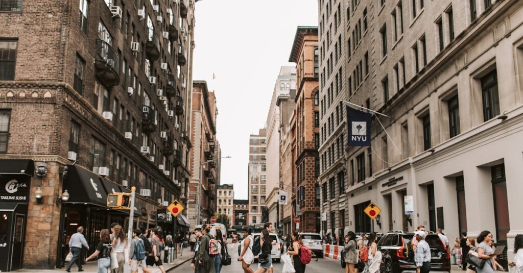 People crossing a New York street lined with historic buildings on a busy day.