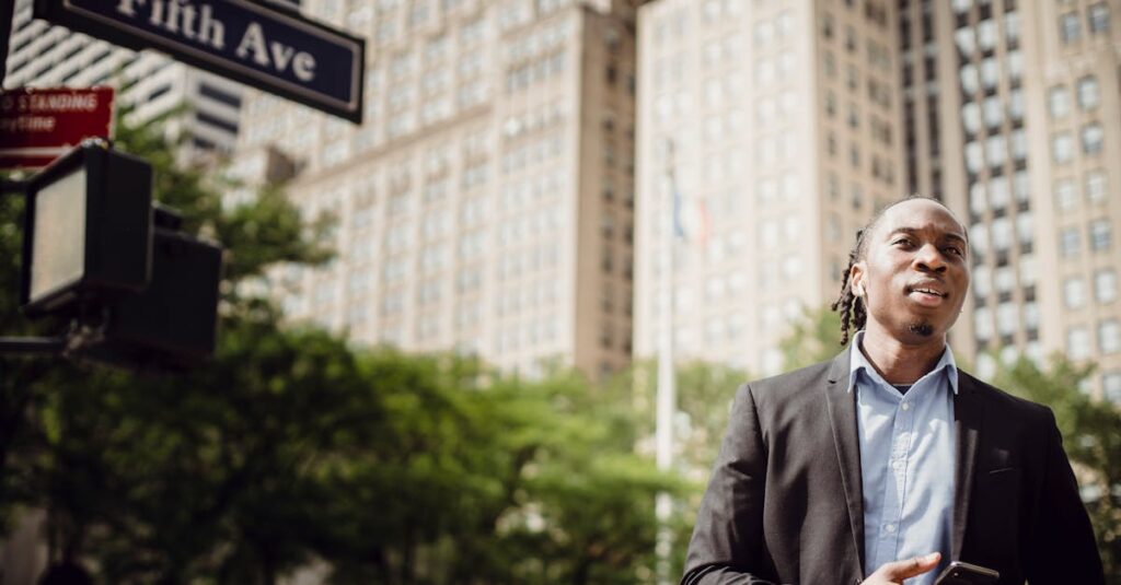 A young man stands on Fifth Avenue in New York City holding a smartphone, showcasing urban lifestyle.