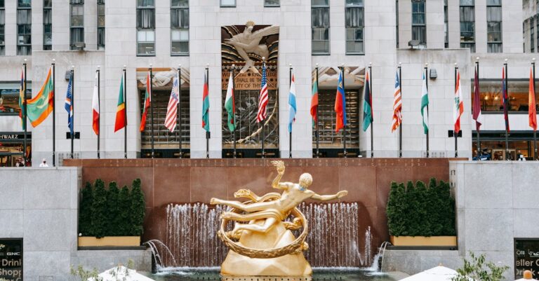 Golden Prometheus statue located near entrance of Rockefeller center with flags on street in New York city in modern district