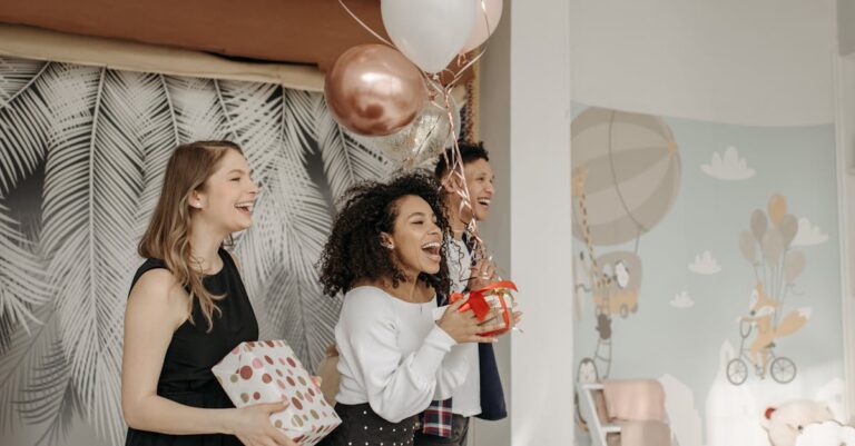 Happy group celebrating a birthday indoors with balloons and presents.