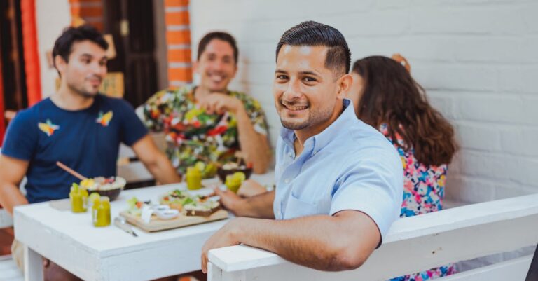 Group of friends enjoying a meal together outdoors at a cafe, smiling and socializing.