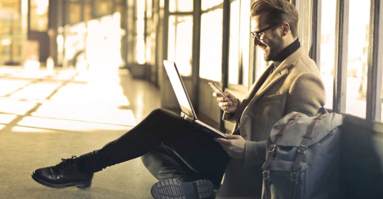 Man sitting with a laptop and smartphone, representing digital nomad lifestyle and remote work.