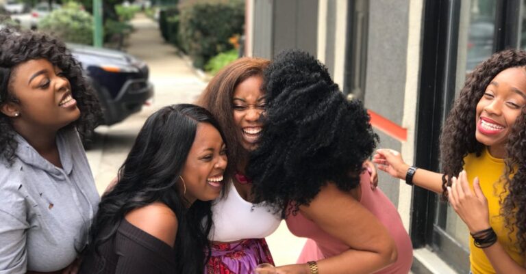 A joyful group of friends sharing a moment of laughter on a sunny day outdoors.