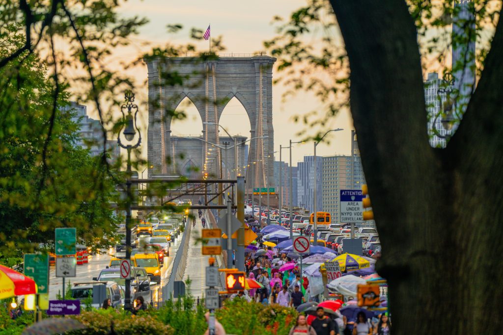 Bustling traffic and pedestrians on a busy day at New York's iconic Brooklyn Bridge.