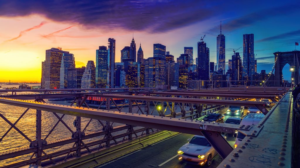 Captivating view of New York City skyline and Brooklyn Bridge illuminated at sunset.