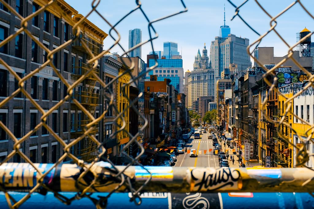 How to Book a Cab From JFK to Manhattan: 7 Honest Facts (2026) 17 Explore a vibrant urban scene through a chain-link fence, capturing New York City's lively streets.