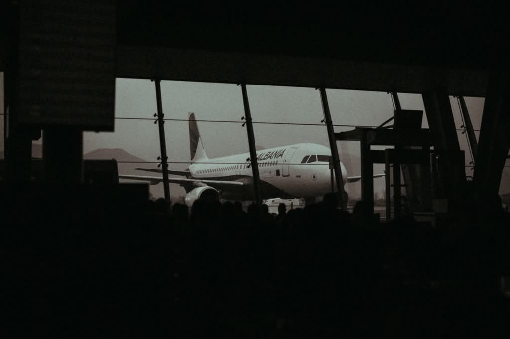 how much is a taxi from jfk to newark airport: 5 Honest Facts for 2026 1 Silhouette of an airplane and waiting passengers inside an airport terminal at dusk.