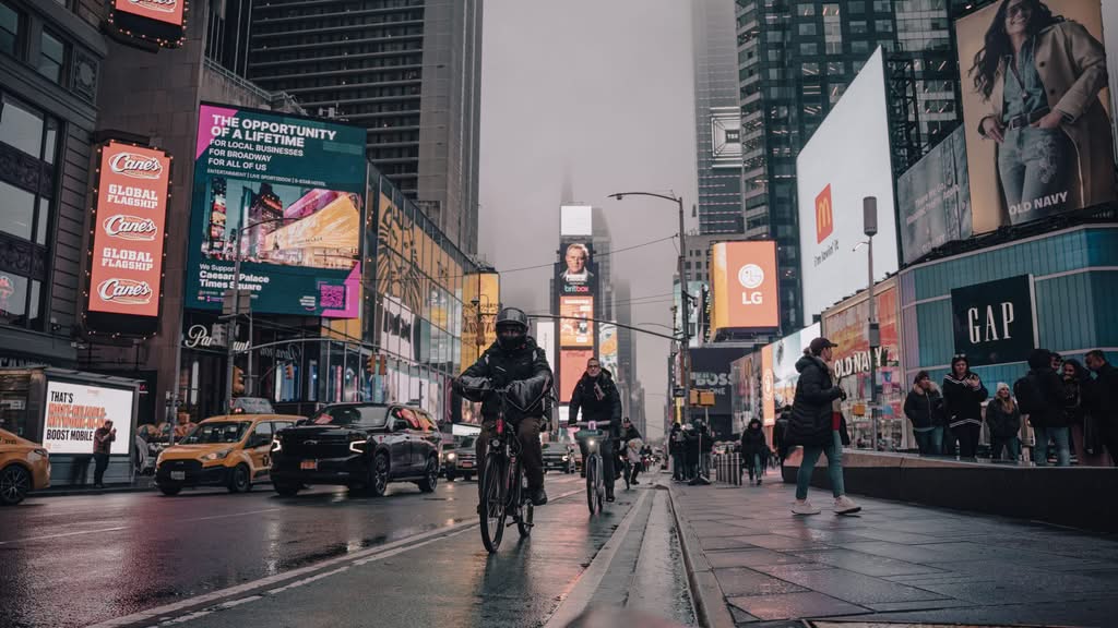 Reliable Manhattan to JFK Taxi: 5 Honest Family Facts 2026 15 A lively evening scene in Times Square, New York City, with cyclists and vibrant advertisements.