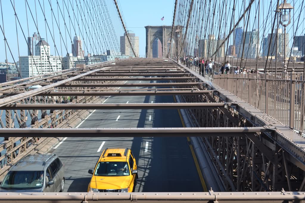 Cab Fare JFK to Manhattan Reviews 2026: 5 Honest Family Facts 15 Yellow taxi crossing Brooklyn Bridge with city skyline in the background on a sunny day.