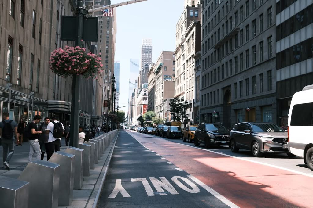 Luxury Upper Car Service NYC: 5 Honest Facts for 2026 11 A lively street in New York City with people, cars, and tall buildings under a clear sky.