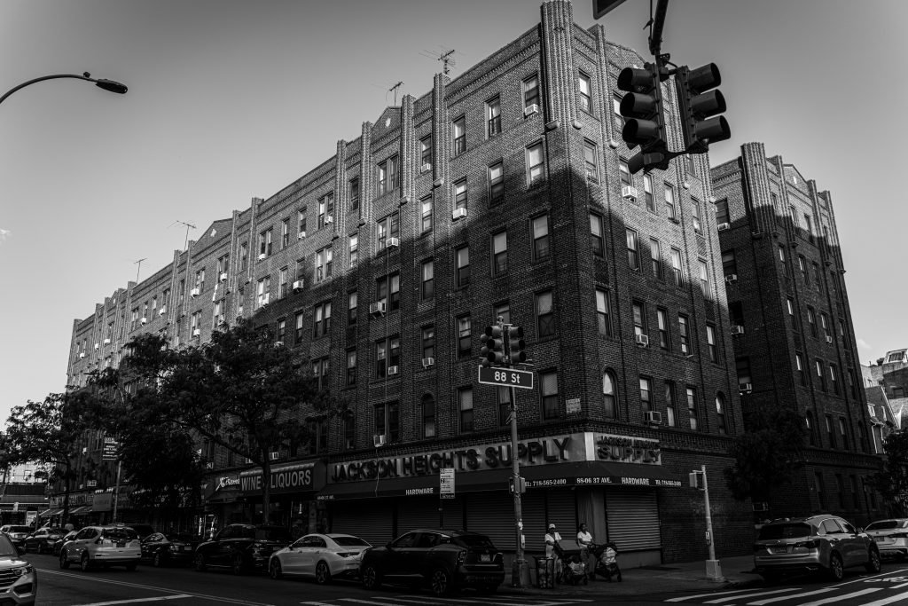 How to Book NY Car Service From LGA: 7 Honest Family Tips 9 Black and white photo of urban architecture in Jackson Heights, New York City with street life.